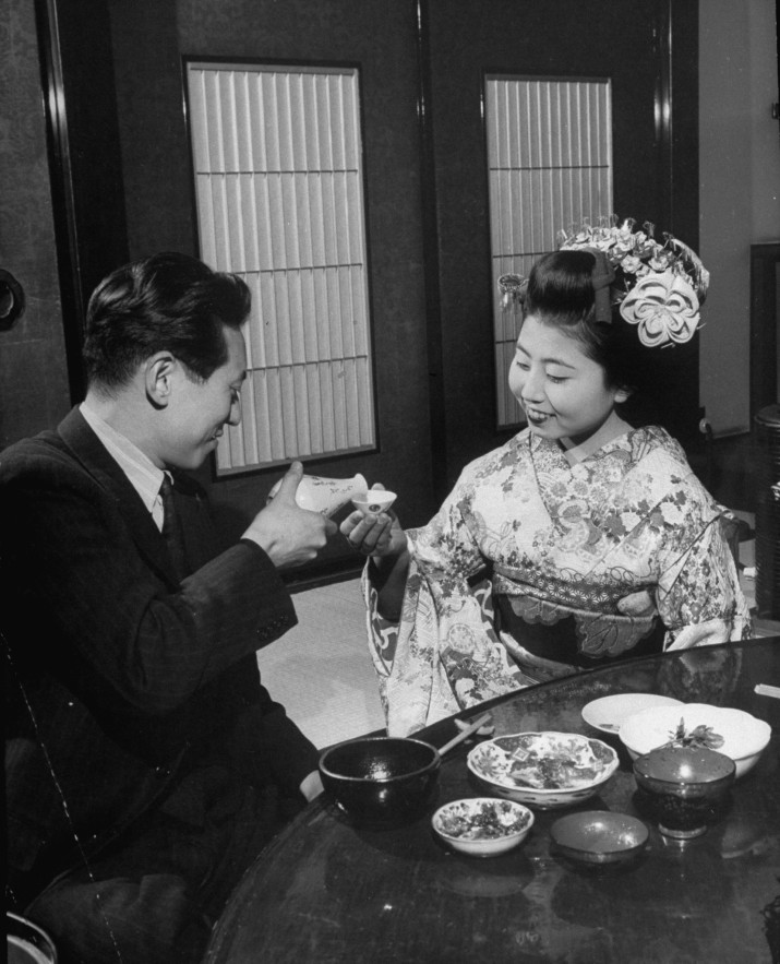 A pleased buisnessman complimenting a novice geisha by giving her his sake cup & pouring some of the rice wine.  (Photo by Alfred Eisenstaedt/Pix Inc./The LIFE Picture Collection/Getty Images)